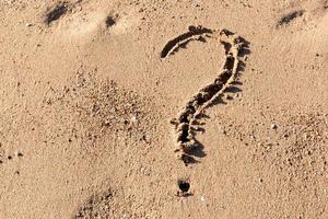 domanda marchio cartello su sabbia spiaggia vicino il mare. concetto di dilemma, risposta e domanda foto