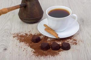 tazza di caffè, piattino, tartufo cioccolatini, cannella bastoni,. foto