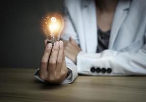 donna d'affari Tenere un' leggero lampadina, creativo nuovo idea. innovazione, brainstorming, soluzione e ispirazione concetti. immaginazione, creativo pensiero problema risolvendo. foto
