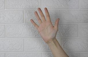 un' donna di Aperto mano evidenziato su un' bianca mattone sfondo foto