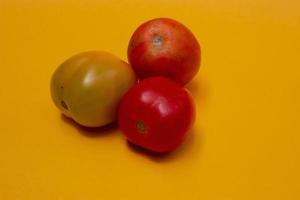 tre pomodori isolato su giallo foto