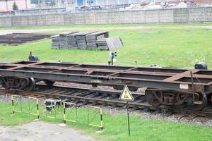 arrugginito vuoto metallo ferro su ruote nolo auto per il treno, locomotiva per il carrozza di merce lungo il rotaie a il ferrovia stazione foto