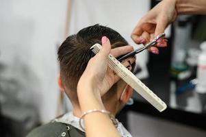 un'adolescente in un salone di bellezza si fa tagliare i capelli, un parrucchiere taglia i capelli a un adolescente. foto