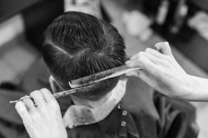 ragazzo adolescente si taglia i capelli durante una pandemia dal barbiere, si taglia i capelli e si asciuga i capelli dopo un taglio di capelli.