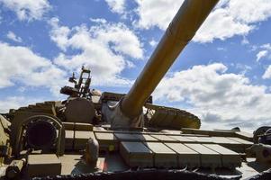 un' grande verde militare metallo blindato mortale pericoloso ferro russo siriano battaglia serbatoio con un' pistola torretta e un' Oca è parcheggiata parcheggiata contro un' blu cielo e nuvole al di fuori il città foto