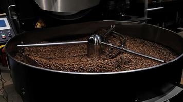 caffè roaster macchina a caffè torrefazione processi. miscelazione caffè fagioli. arrostito Filatura più fresco professionale macchine e fresco Marrone caffè fagioli movimento avvicinamento buio foto a fabbrica.