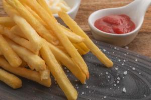 francese patatine fritte nel taglio tavola ha Maionese e pomodoro salsa su legna sfondo malsano cibo concetto. foto