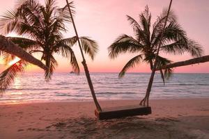 legna swing con palma albero su il tropicale spiaggia tramonto al di sopra di il mare per viaggio nel vacanza rilassare volta, foto