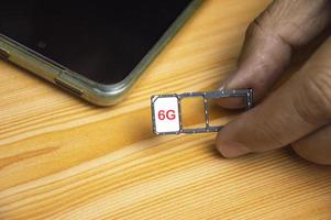 6g tecnologia, Internet concetto. sim carta nel smartphone vassoio su di legno tavolo, avvicinamento 6g Rete concetto, alto velocità mobile Internet nuovo età Rete, attività commerciale concetto foto