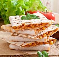 quesadilla messicana affettata con verdure e salse sul tavolo foto