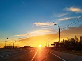 tramonto su il autostrada. asfalto strada nel sole raggi. vuoto traccia nel il luce del sole foto