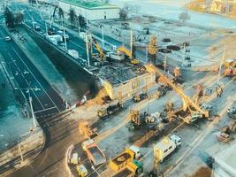 costruzione di un' nuovo cavalcavia nel il città centro su un' nevoso strada. strada riparazione, costruzione di un' ponte con costruzione attrezzatura, enorme giallo gru foto