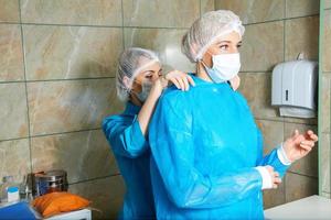 assistente indossare maschera e chirurgo preparazione per chirurgia foto