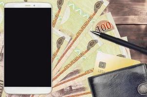 100 domenicano peso fatture e smartphone con borsa e credito carta. pagamenti elettronici o e-commerce concetto. in linea shopping e attività commerciale con portatile dispositivi foto