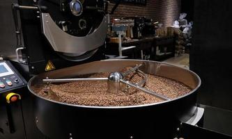 caffè roaster macchina a caffè torrefazione processi. miscelazione caffè fagioli. arrostito Filatura più fresco professionale macchine e fresco Marrone caffè fagioli movimento avvicinamento buio foto a fabbrica.