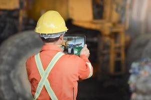 ingegnere lavoratore nel protettivo uniforme e con elmetto protettivo utilizzando tavoletta per controllo Lavorando. raccolta differenziata industria. foto