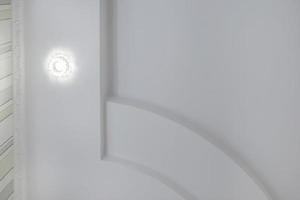 dettaglio di angolo soffitto con intricato corona modanatura. sospeso soffitto e cartongesso costruzione nel vuoto camera nel appartamento o Casa. allungare soffitto bianca e complesso forma. foto