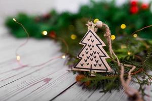 mestiere regalo di legno Natale albero pendente su un' sfondo di bokeh Natale ghirlande e Natale albero. Natale albero decorazione nel il modulo di un' Natale albero avvicinamento foto