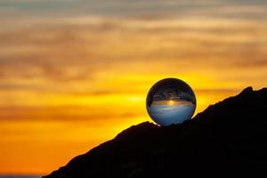 palla di vetro su una roccia al tramonto foto