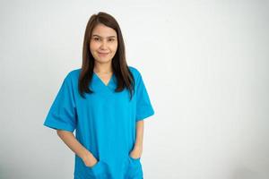 ritratto di fiducioso, felice, e sorridente asiatico medico donna medico o infermiera indossare blu scrub uniforme al di sopra di isolato bianca sfondo foto