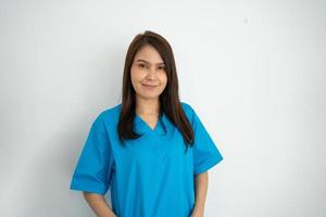 ritratto di fiducioso, felice, e sorridente asiatico medico donna medico o infermiera indossare blu scrub uniforme al di sopra di isolato bianca sfondo foto