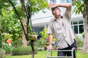 felice vecchio anziano asiatico usa un deambulatore e cammina nel cortile. concetto di felice pensionamento con la cura di un caregiver e risparmi e assicurazione sanitaria senior foto