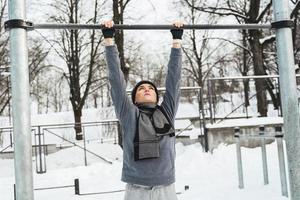 atletico donna fare pull-up su orizzontale bar durante all'aperto inverno allenarsi foto