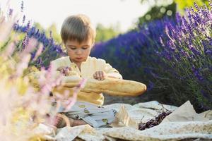 carino Affamato bambino mangiare pane durante picnic nel un' lavanda campo foto