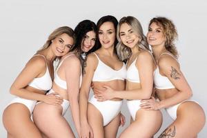gruppo di diverso donne indossare bianca biancheria intima su grigio sfondo. foto