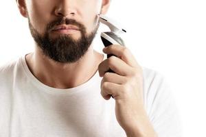 barbuto uomo è utilizzando elettrico trimmer foto