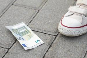 femmina piede e cinque Euro banconota su il terra foto