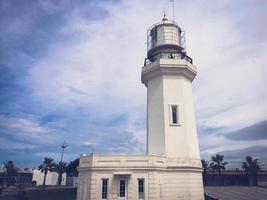 grande alto pietra bianca faro su il tropicale mare caldo estate ricorrere con palma alberi contro il blu cielo foto