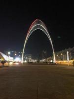 un' grande bellissimo metallico moderno luminoso moderno arco di il nero mare è il Ingresso per il batumi botanico giardino a notte. batumi, Georgia, aprile 17, 2019 foto