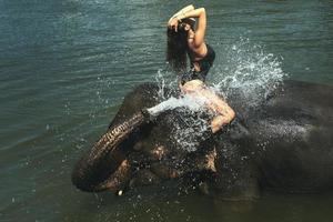 contento donna è bagnarsi con il elefante nel il fiume foto