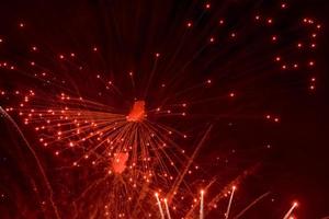 saluto. luminosa, rosso spruzzi di fuochi d'artificio nel il buio cielo. foto