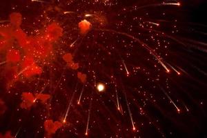 saluto. luminosa, rosso spruzzi di fuochi d'artificio nel il buio cielo. foto