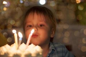 carino ragazzo colpi su candele su il suo terzo compleanno. il del bambino compleanno. foto