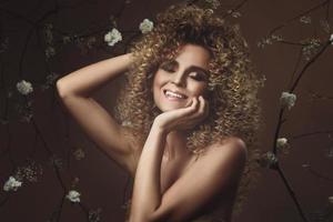 bello giovane donna con afro acconciatura e bellissimo trucco con un' lotto di bianca fiori foto