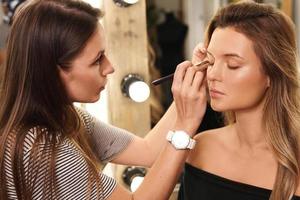 professionale trucco artista e sua Lavorando processi durante trucco routine per giovane e bellissimo modello foto