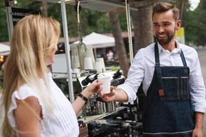 barista uomo dando tazza di caffè per donna cliente foto