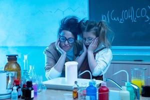 insegnante e poco ragazza durante chimica lezione miscelazione sostanze chimiche nel un' laboratorio foto