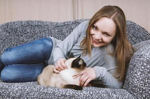 contento giovane donna rilassante su divano con gatto foto