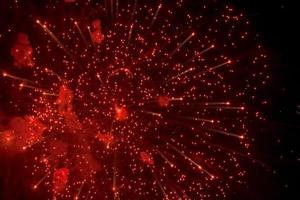 saluto. luminosa, rosso spruzzi di fuochi d'artificio nel il buio cielo. foto