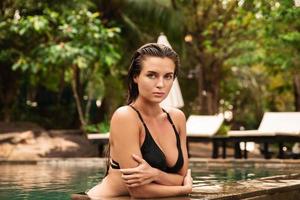 giovane donna indossare nero bikini è rilassante nel il nuoto piscina foto