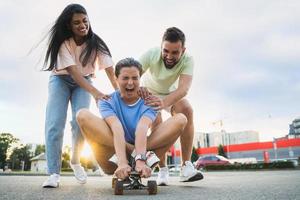 diverso spensierato amici avendo divertimento e equitazione longboard su parcheggio lotto foto