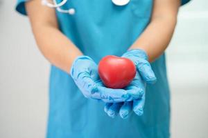 medico che tiene un cuore rosso nel reparto ospedaliero, concetto medico sano e forte. foto