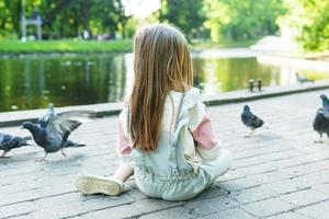 poco ragazza alimentazione uccelli nel un' città parco foto