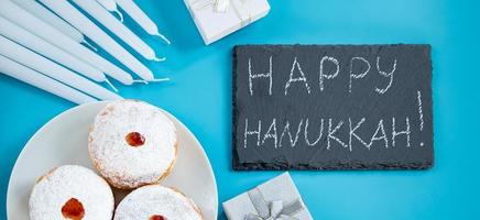 contento hanukkah. ebraico dolce sufganiyot ciambelle su blu sfondo. simbolo di religioso giudaismo vacanza. iscrizione su gesso tavola. foto