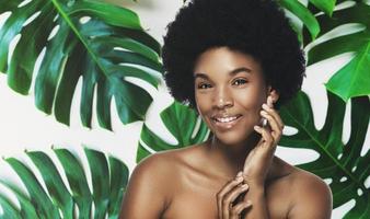 giovane e bellissimo africano donna con Perfetto liscio pelle nel tropicale le foglie foto