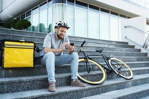 esprimere cibo consegna Corriere seduta su il le scale con isolato Borsa e bicicletta. foto